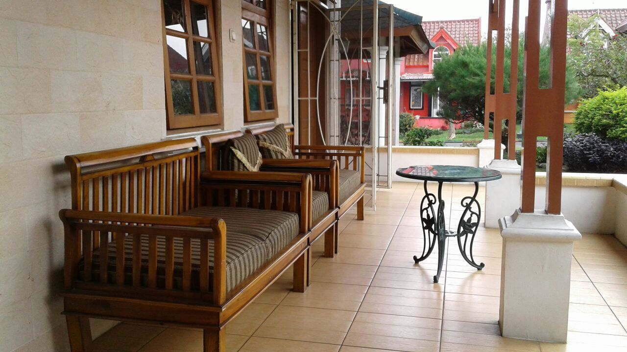 Une terrasse couverte, aménagée avec des meubles en bois et une table en verre.