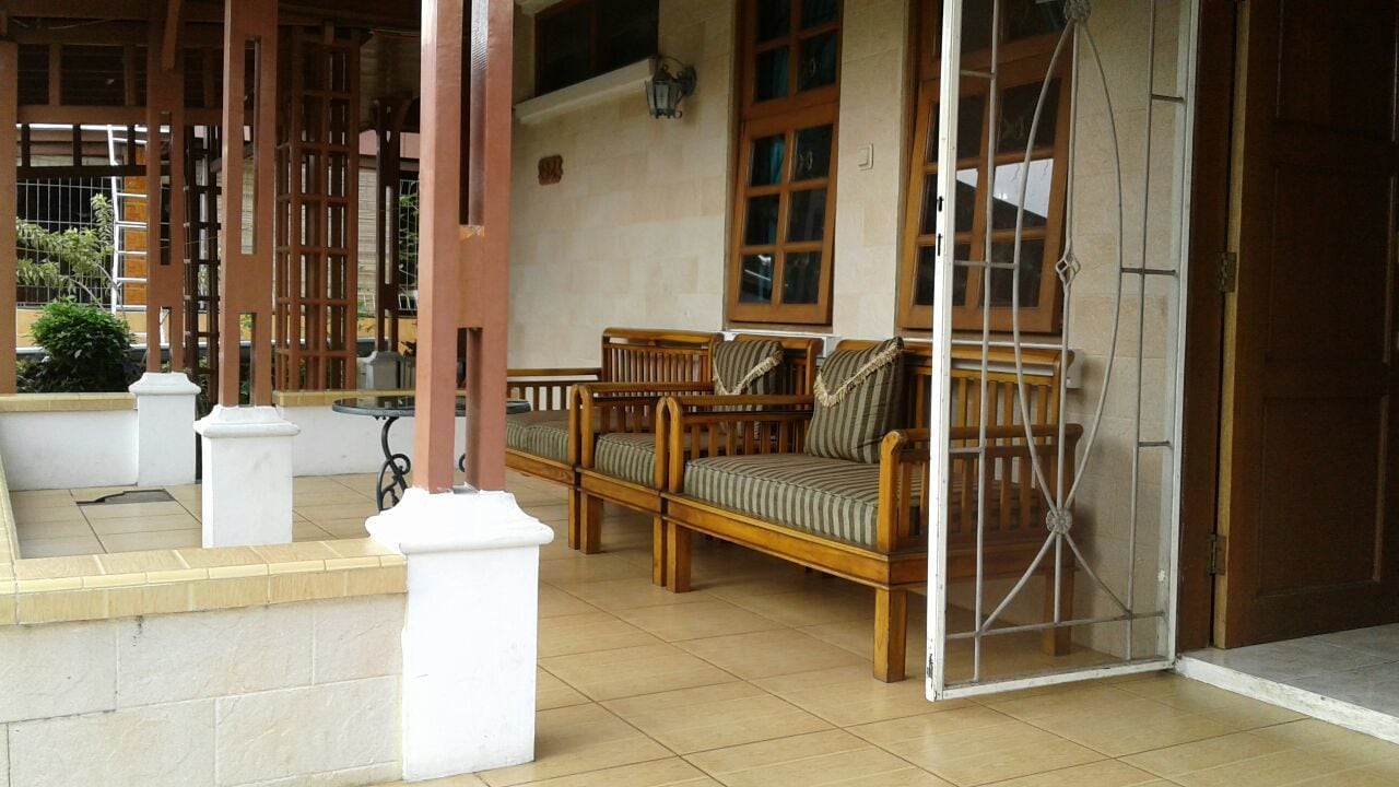 A covered outdoor seating area with wooden furniture and a tiled floor.