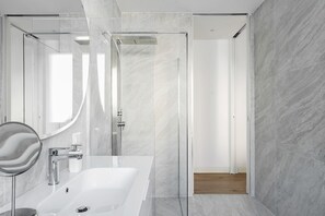 Features a sleek sink, large mirror, and glass-enclosed shower area.