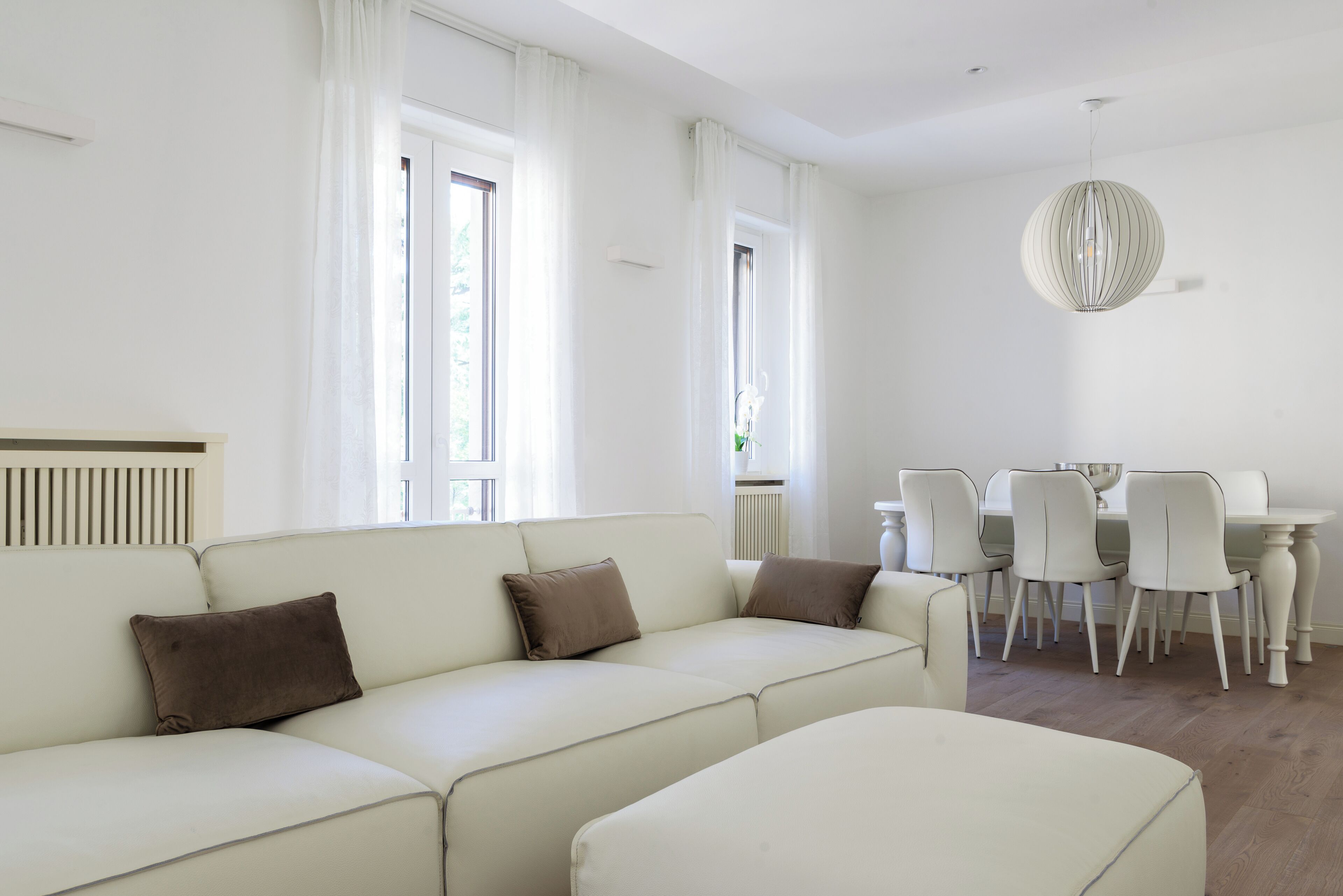 Un salon moderne avec un canapé, une table à manger et des chaises, ainsi qu’un luminaire suspendu.