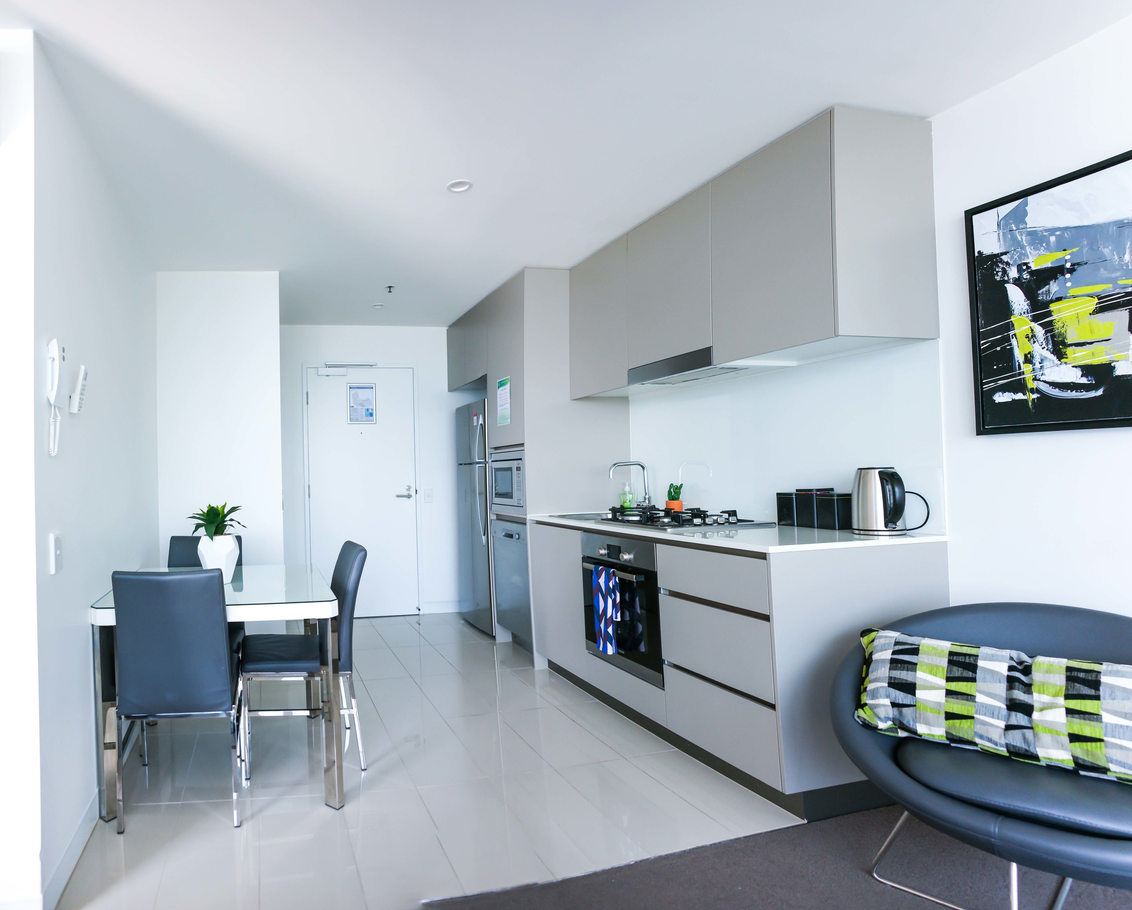 A modern kitchen with a dining area, a sofa, and a painting on the wall.