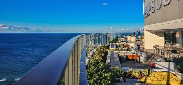 A rooftop terrace with outdoor seating and a view of the ocean.