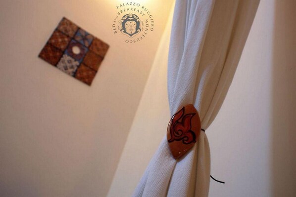 A curtain with a decorative brooch and a wall with a logo and a patterned artwork.