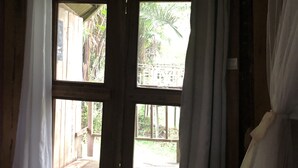 A room with wooden walls and a window with curtains. - Oveng Lodge (Nkolmétet)