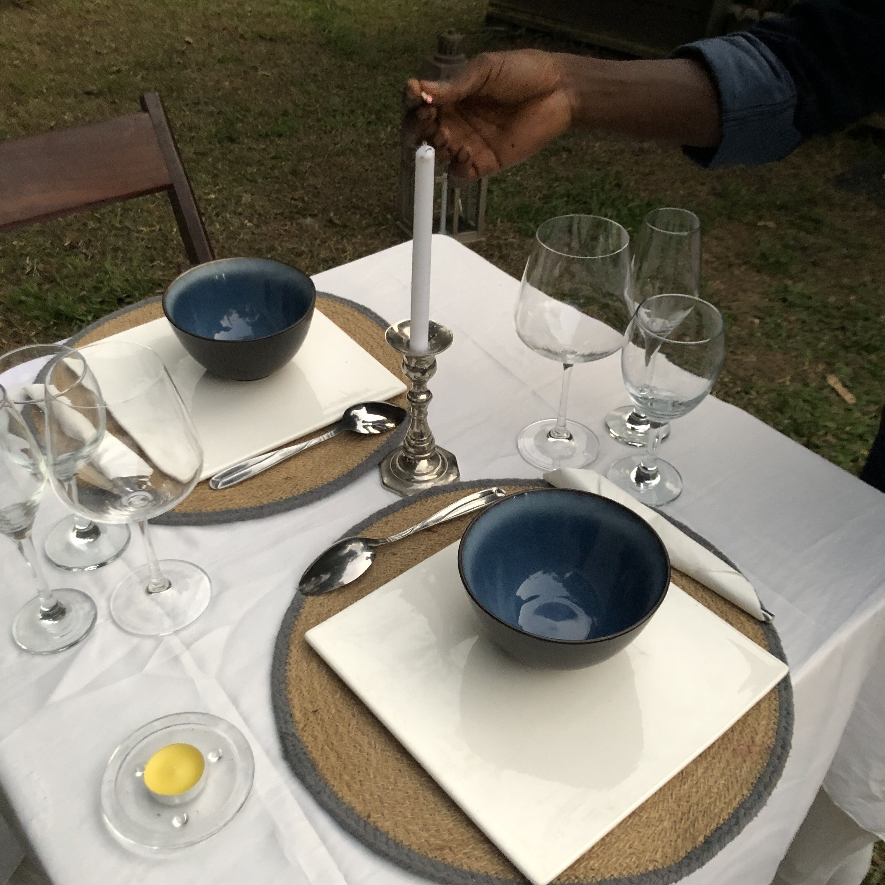Una mesa dispuesta con fuentes azules, copas de vino y cubiertos.