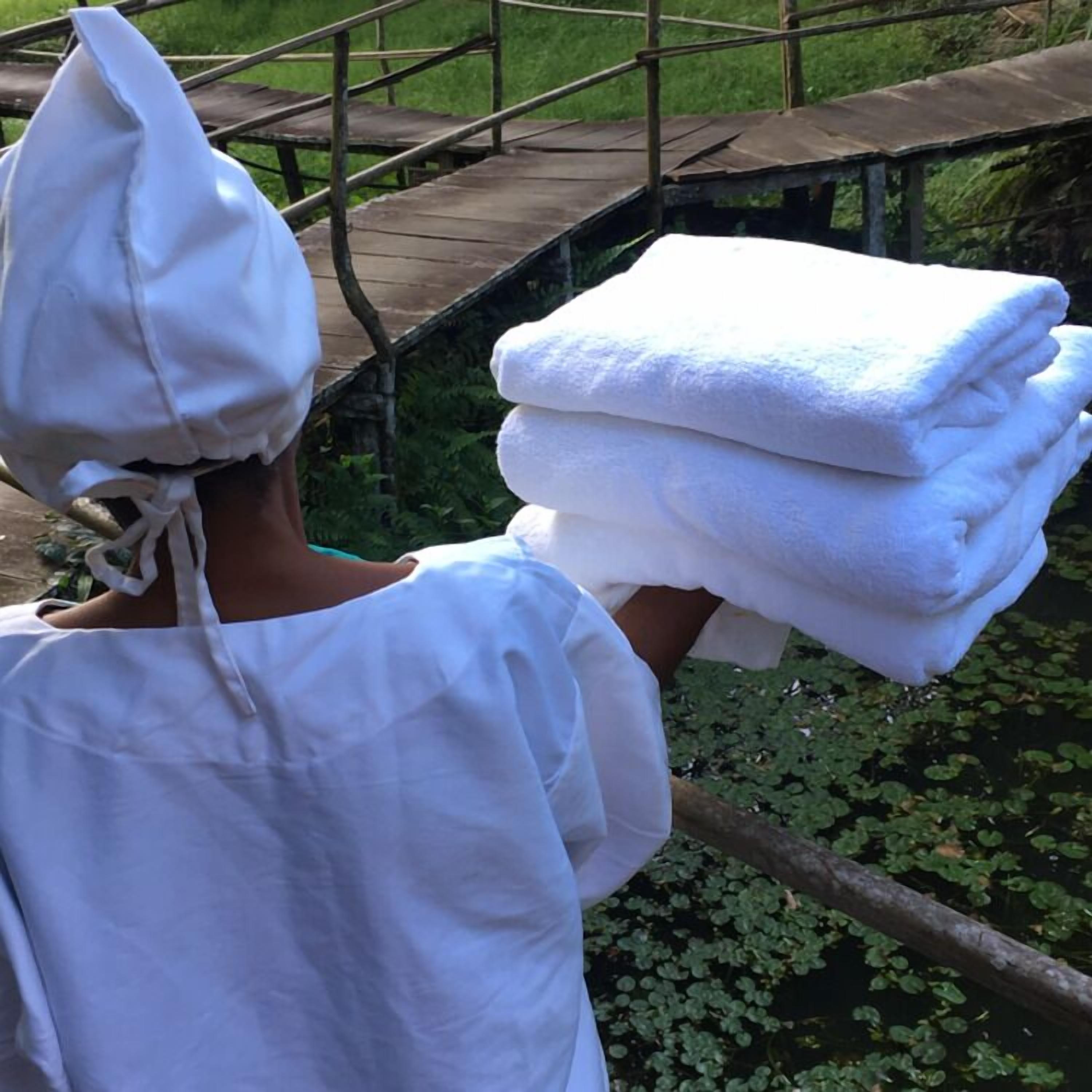 Una persona cargando una pila de toallas blancas.