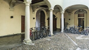 A courtyard with multiple arches, a row of bicycles, and a cobblestone floor.