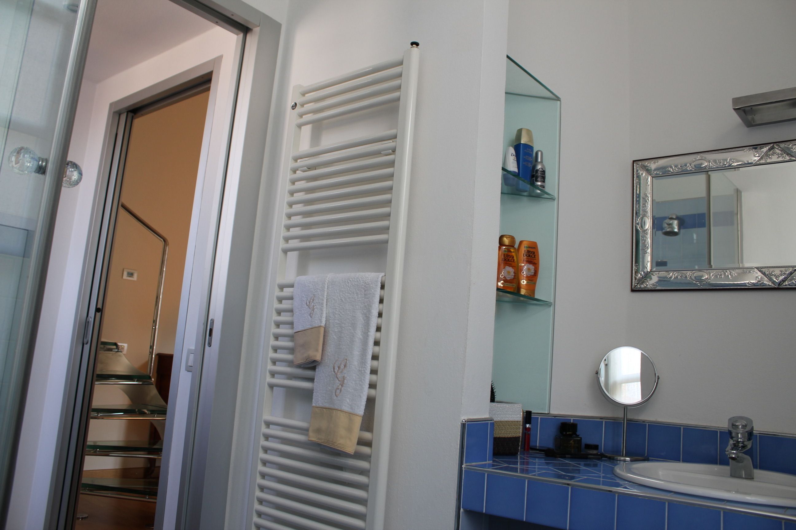 A bathroom with a white towel rack, a mirror, and a sink with blue tiles.