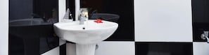 A bathroom with a white sink, black and white tiled walls, and a mirror.