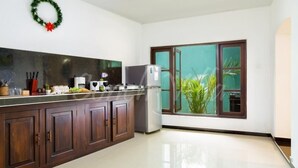 A modern kitchen with dark wooden cabinets, a stainless steel refrigerator, and a large window with a view of greenery. - Grand Conch Villa (Tangalle)