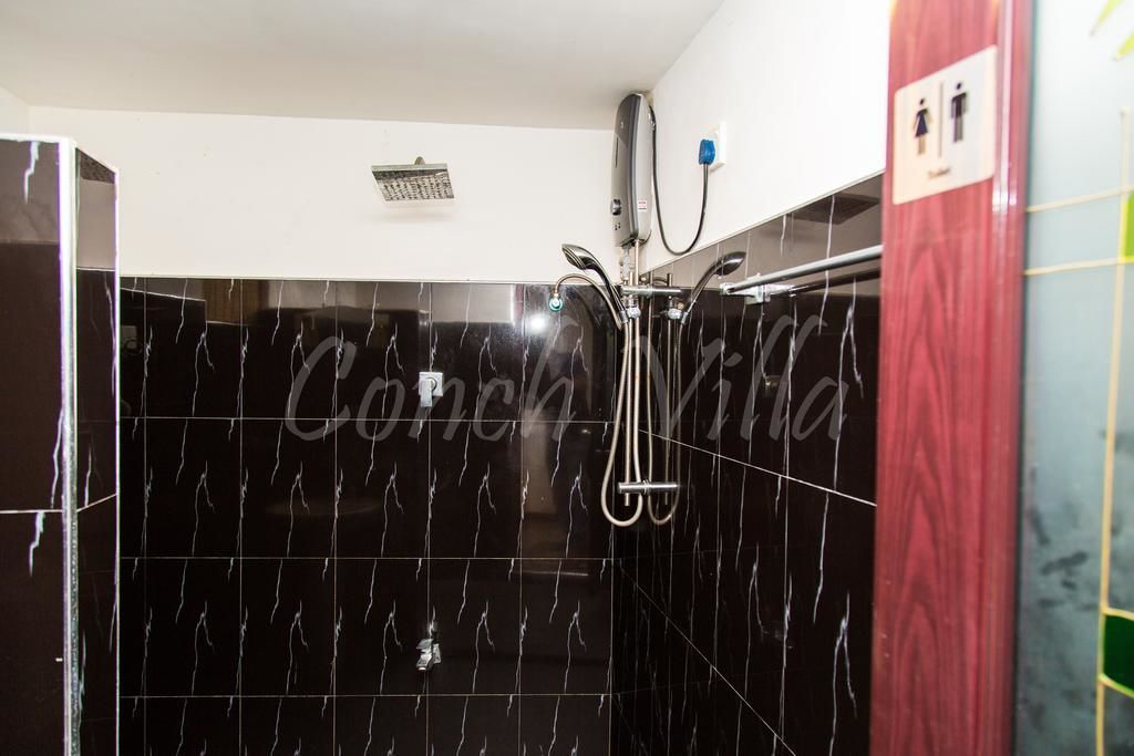 Une salle de bain avec des carreaux de marbre noir, une douche et des toilettes.