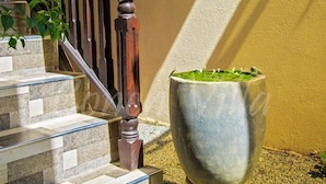 A staircase with a wooden handrail and a potted plant beside it. - Grand Conch Villa (Tangalle)