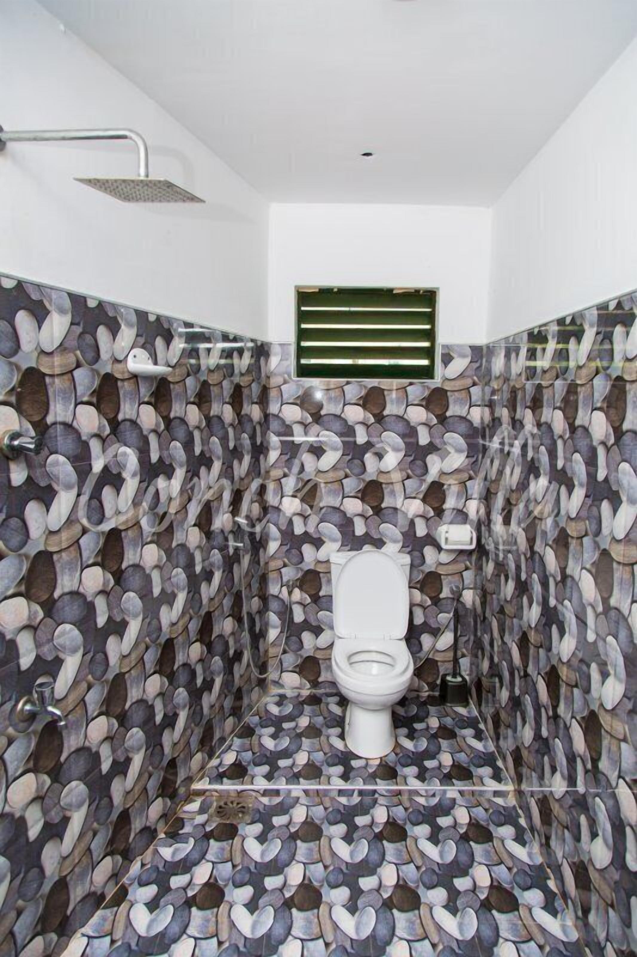 A bathroom with a stone-patterned wall and a showerhead.