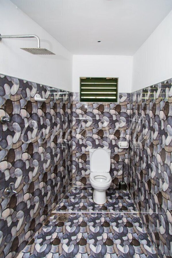 Une salle de bain avec un mur décoré d’un motif imitant la pierre et une pomme de douche.