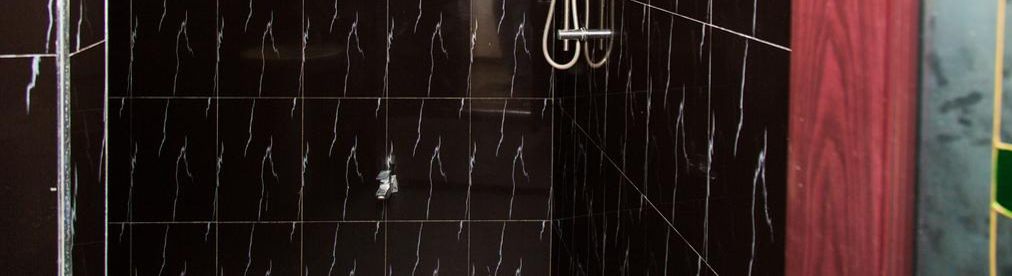 Ein Badezimmer mit schwarzen Marmorfliesen und einer Duschkabine.