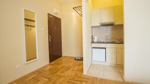 Un pasillo con piso de madera que conduce a una cocina con fregadero, estufa y armarios.