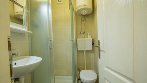 Un baño pequeño y funcional con lavamanos, inodoro y cabina de ducha.