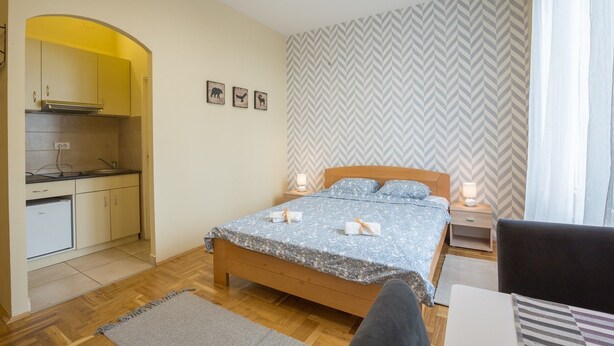 Un dormitorio con cama, mesitas de noche y vista a una zona de cocina.
