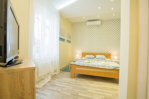 Un dormitorio con una cama, un televisor sobre un escritorio de madera y un aire acondicionado en la pared.