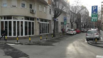 Vista de la calle con un edificio identificado como 'Hyakuni' y una señal de estacionamiento que indica una zona de aparcamiento.