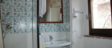 Un baño con ducha, lavamanos y ventana.