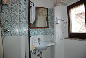 A bathroom with a shower, sink, and a window.