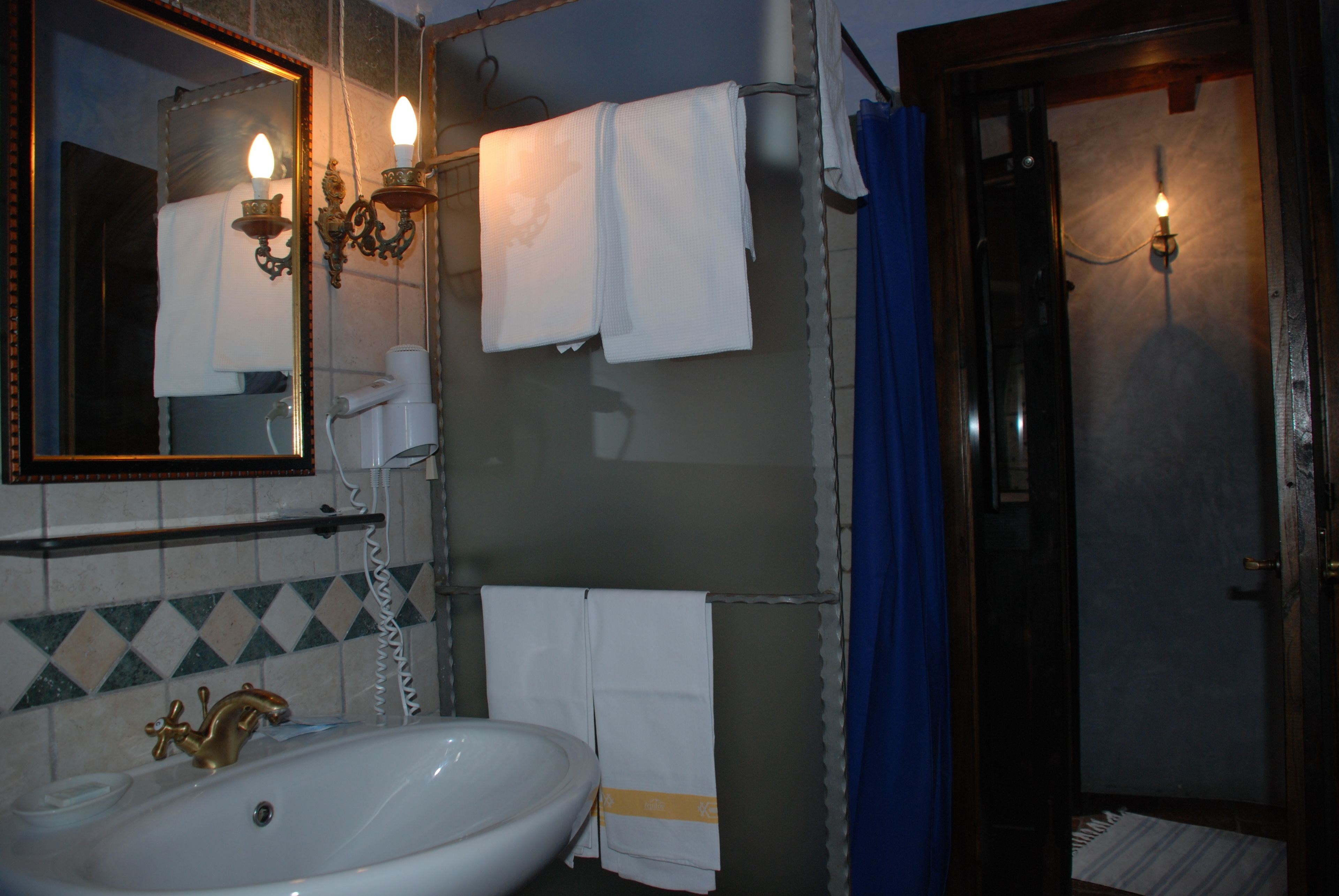 Ein Badezimmer mit Waschbecken, Spiegel, Handtuchhalter und Duschvorhang.