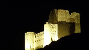 A historic castle with illuminated walls and towers, situated on a hill.