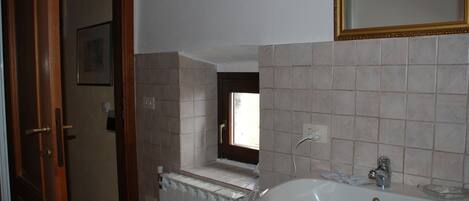 A bathroom with a white sink, a mirror, and a window.
