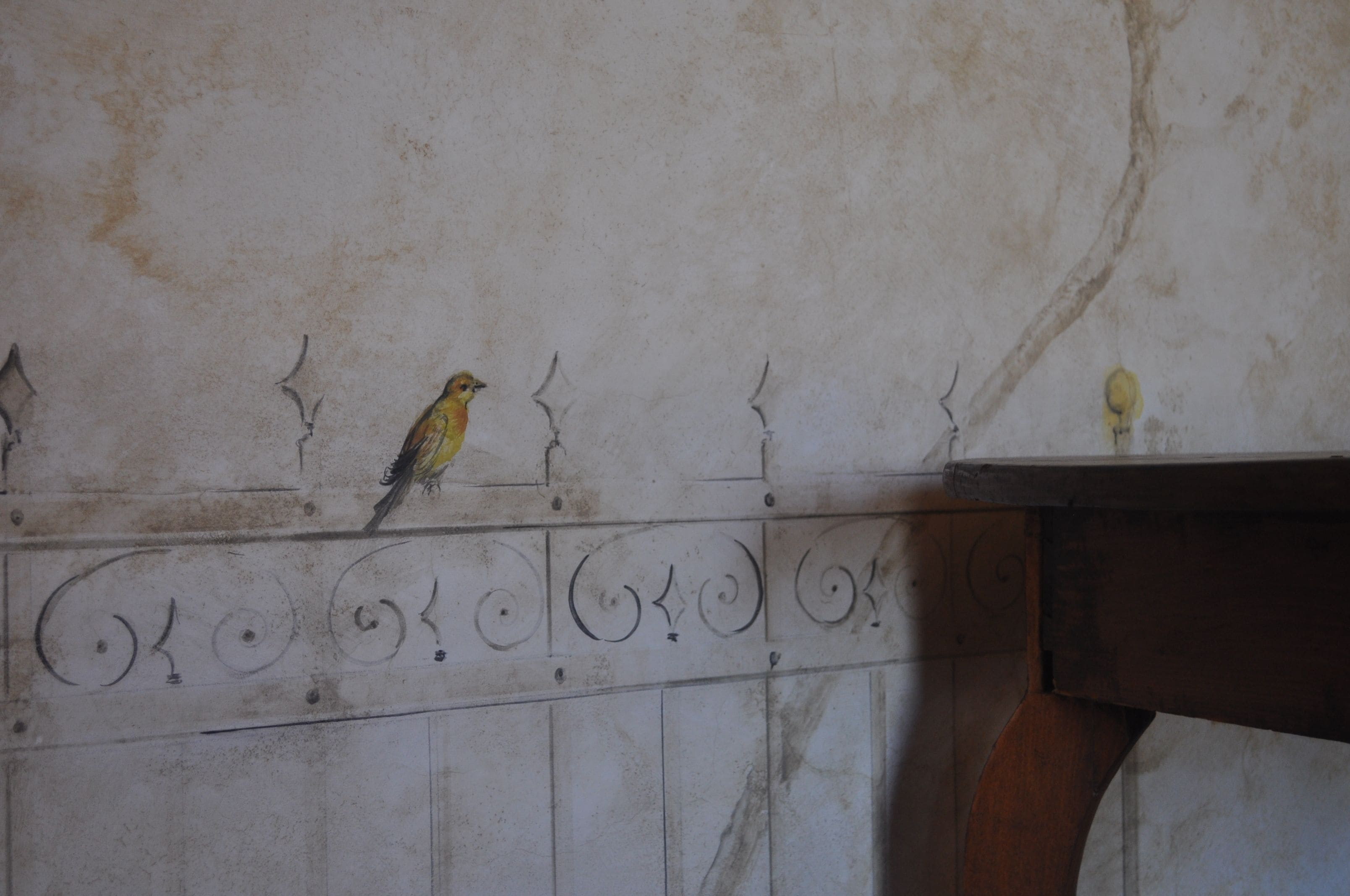A bird perched on a wall with decorative moldings.
