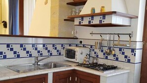 A kitchen with a white and blue tiled backsplash, a stove, a sink, and wooden cabinets.