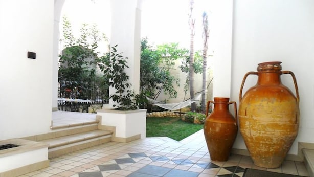 A tiled patio area with steps leading to a hammock and a large vase.