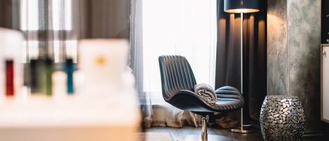 A modern room with a dark leather chair, a floor lamp, and a textured vase on a wooden floor.