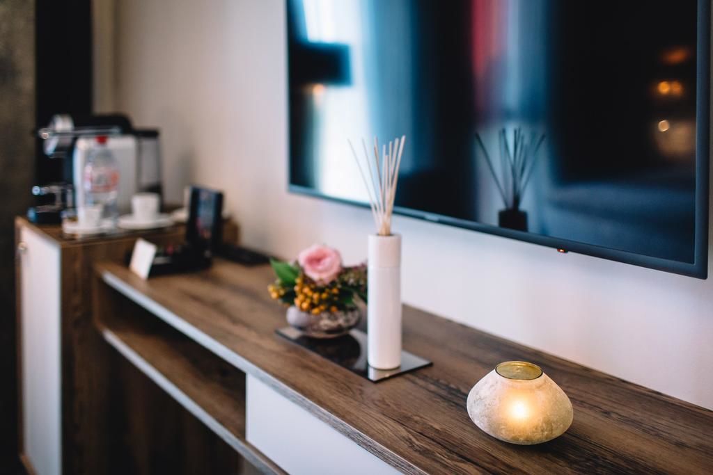 Un comptoir d’accueil en bois, avec une machine à café, un vase contenant une fleur rose et une bougie allumée.