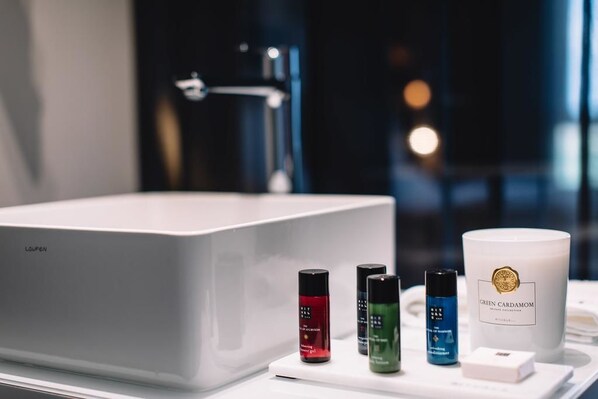 A bathroom with a white bathtub, a sink, and a vanity with skincare products.