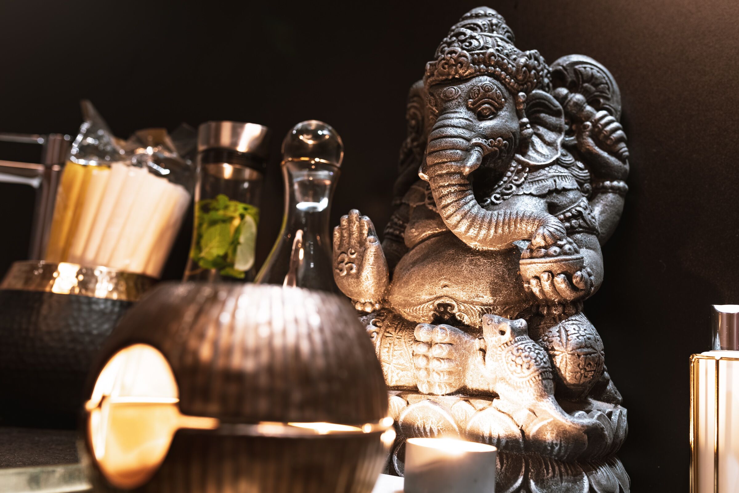 A statue of an elephant deity, surrounded by various metallic objects and containers.