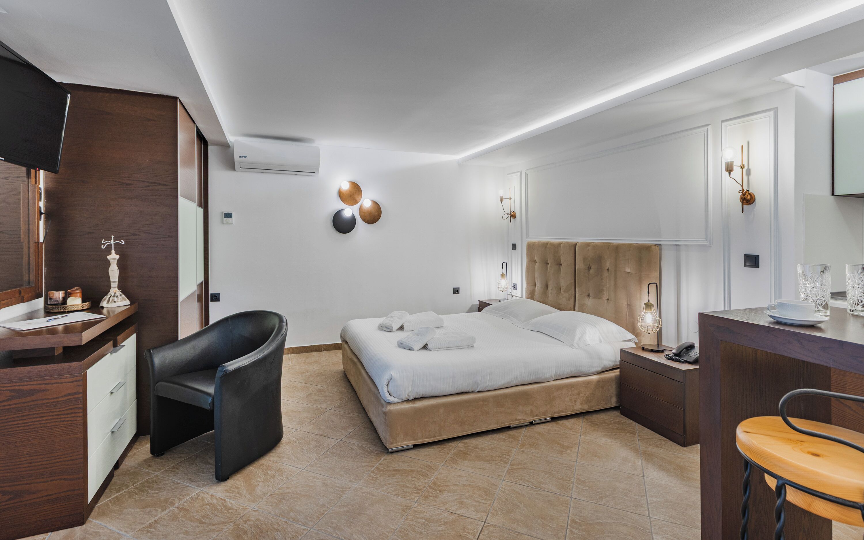 Una habitación de hotel moderna con cama, escritorio, silla y un espejo grande.