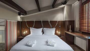Una habitación de hotel con una cama grande, cabecera de madera, dos lámparas de noche y una ventana con persianas.