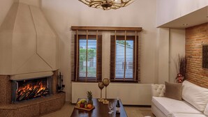 A spacious living room with a fireplace, a large chandelier, and a cozy seating area. - Vintage Suites Trikala (Trikala)