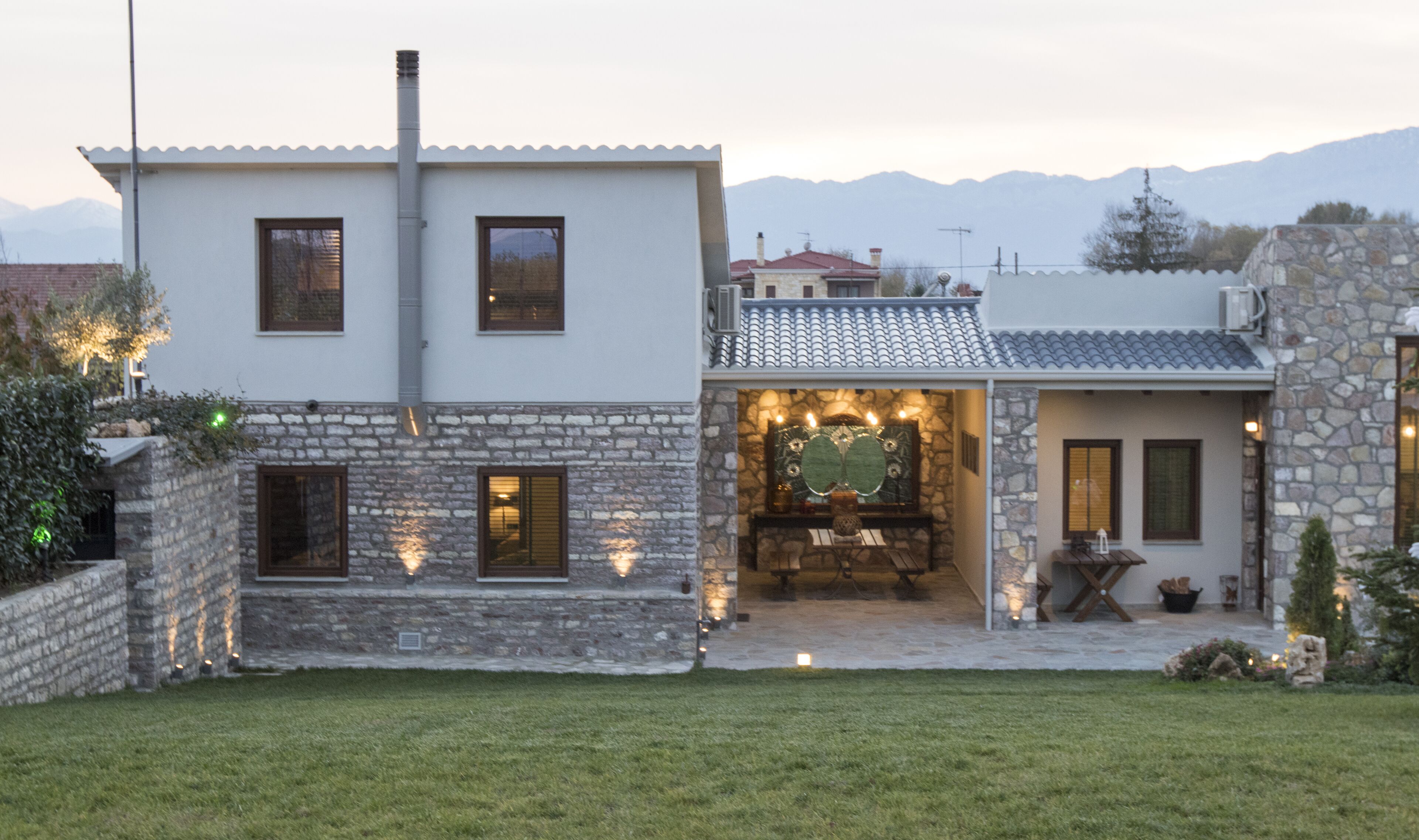 Una casa de dos plantas con paredes de piedra y tejado de baldosas.