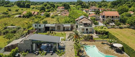 A large estate with a swimming pool, outdoor seating, and a vineyard.
