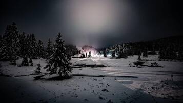 A snowy landscape with a cabin in the distance.