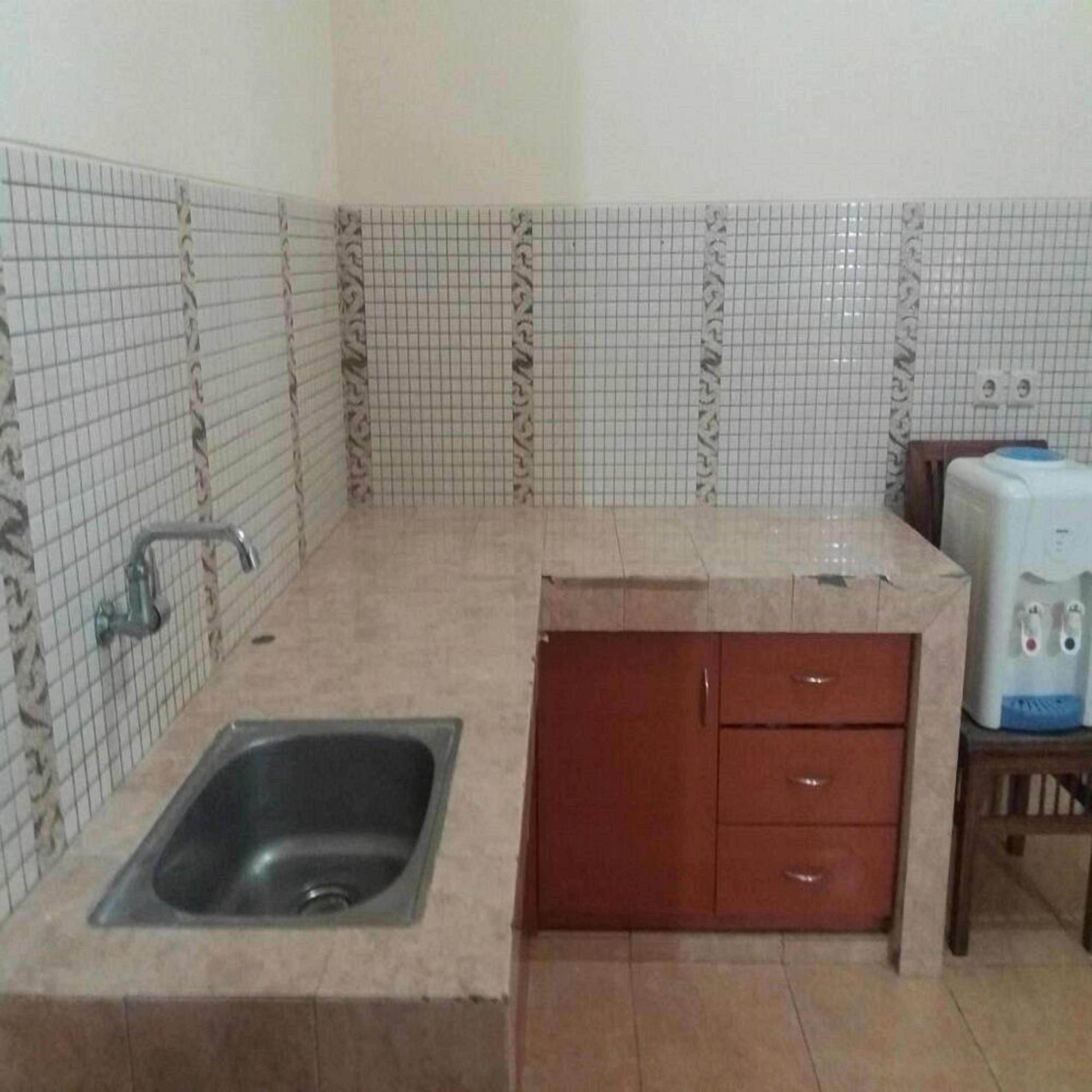 A kitchen with a sink, a countertop, a water dispenser, and a cabinet.