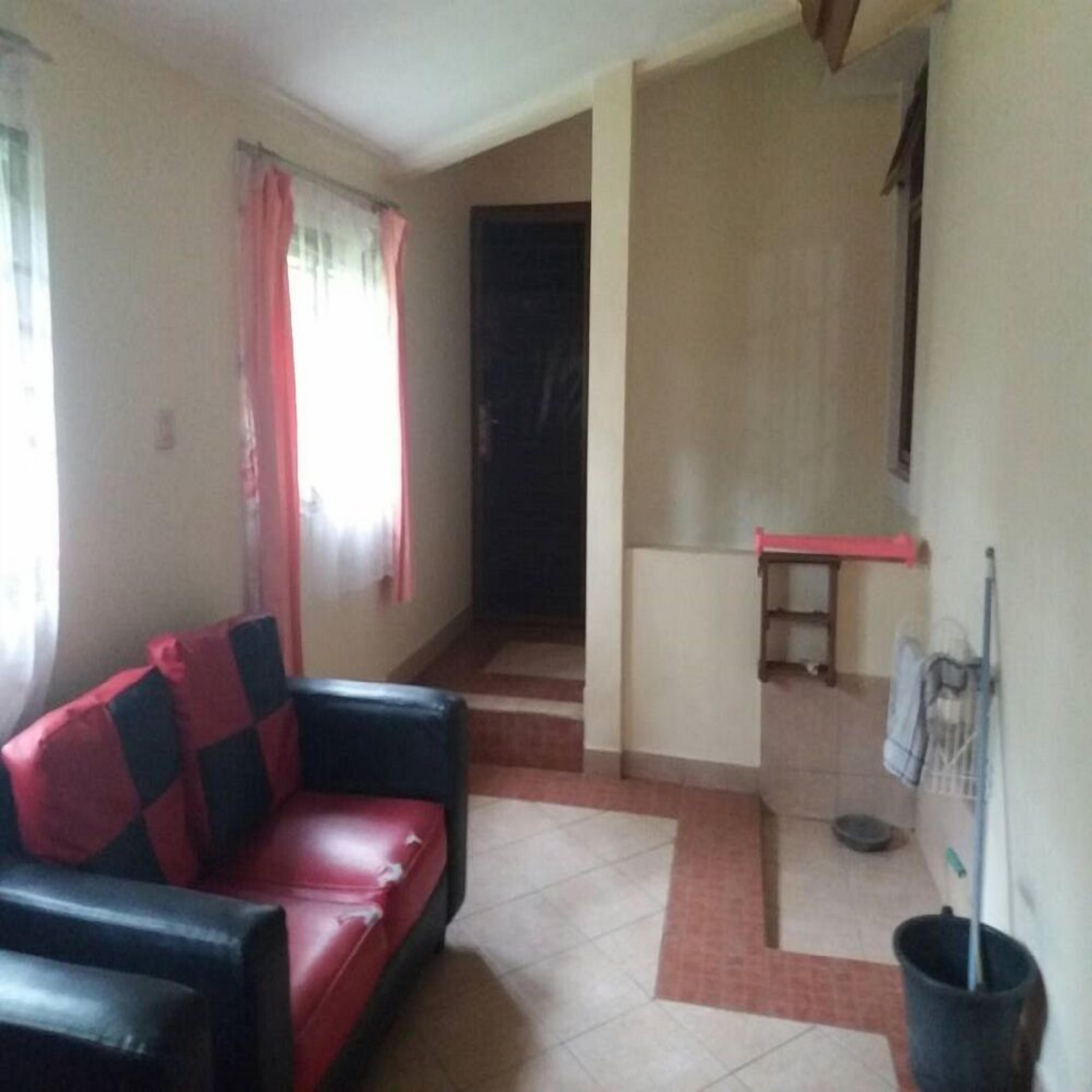 Ein Wohnzimmer mit einem roten und schwarzen Sofa, einem kleinen Tisch und einer schwarzen Mülltonne.