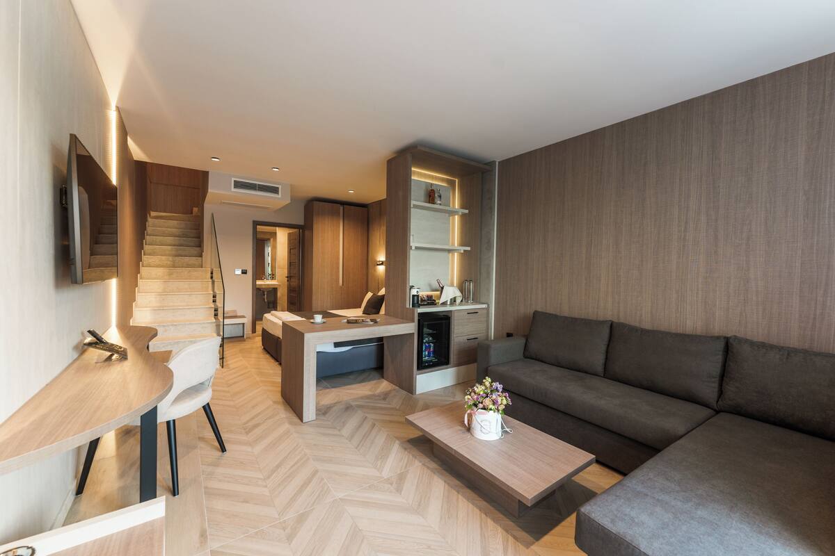 A modern living room with a sofa, coffee table, and a dining area with a table and chairs.