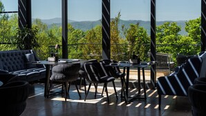 Un espace extérieur aménagé de façon moderne, offrant une vue sur des collines verdoyantes et des montagnes.