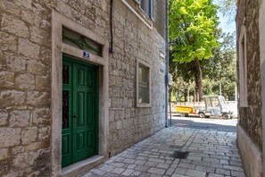 A narrow stone building with a green door and a small window. - Pellegrini Luxury Rooms (Split)