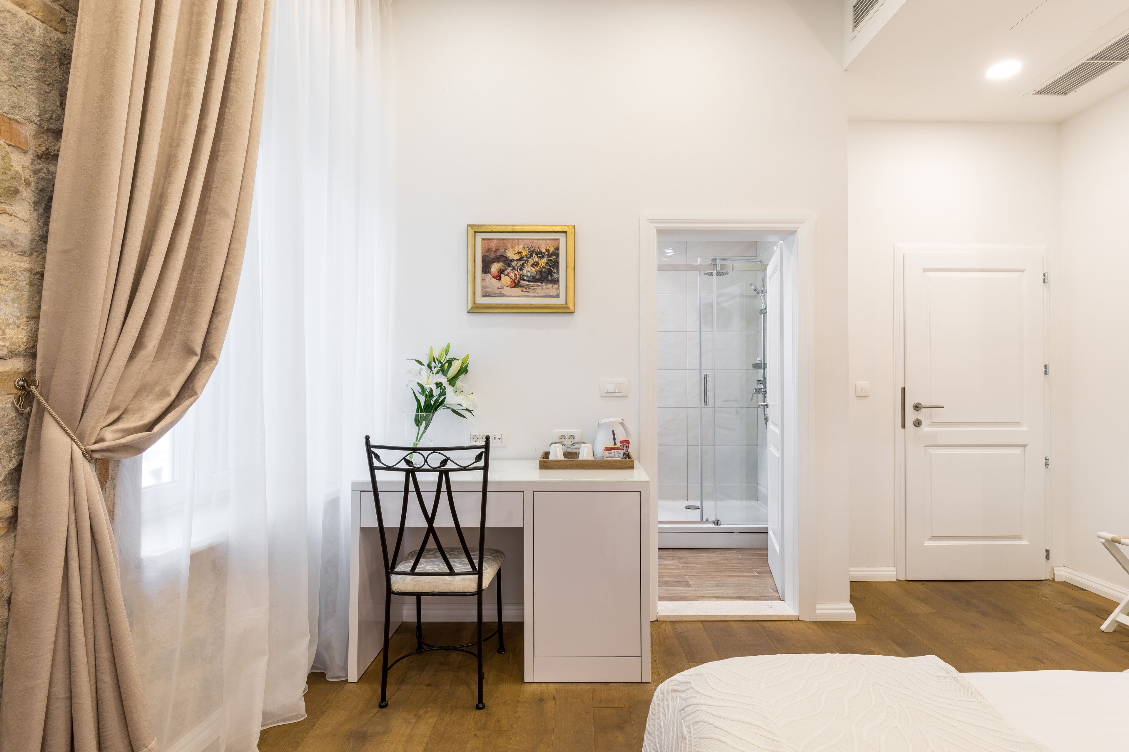 Ein Schlafzimmer mit einem Bett, einem Schreibtisch mit Stuhl, einer Dusche und einer Tür.