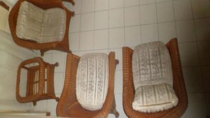 Una habitación con piso de baldosas y cuatro sillas de madera con cojines blancos.