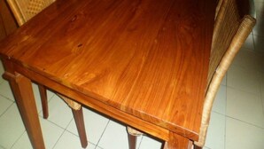 Una mesa de comedor de madera con sillas, un sofá y un televisor en una sala de estar.